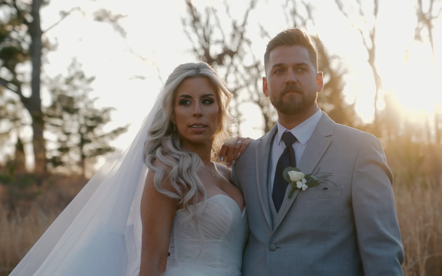 Alley & Nate side by side in a winter field, the low sun burning through the trees behind them