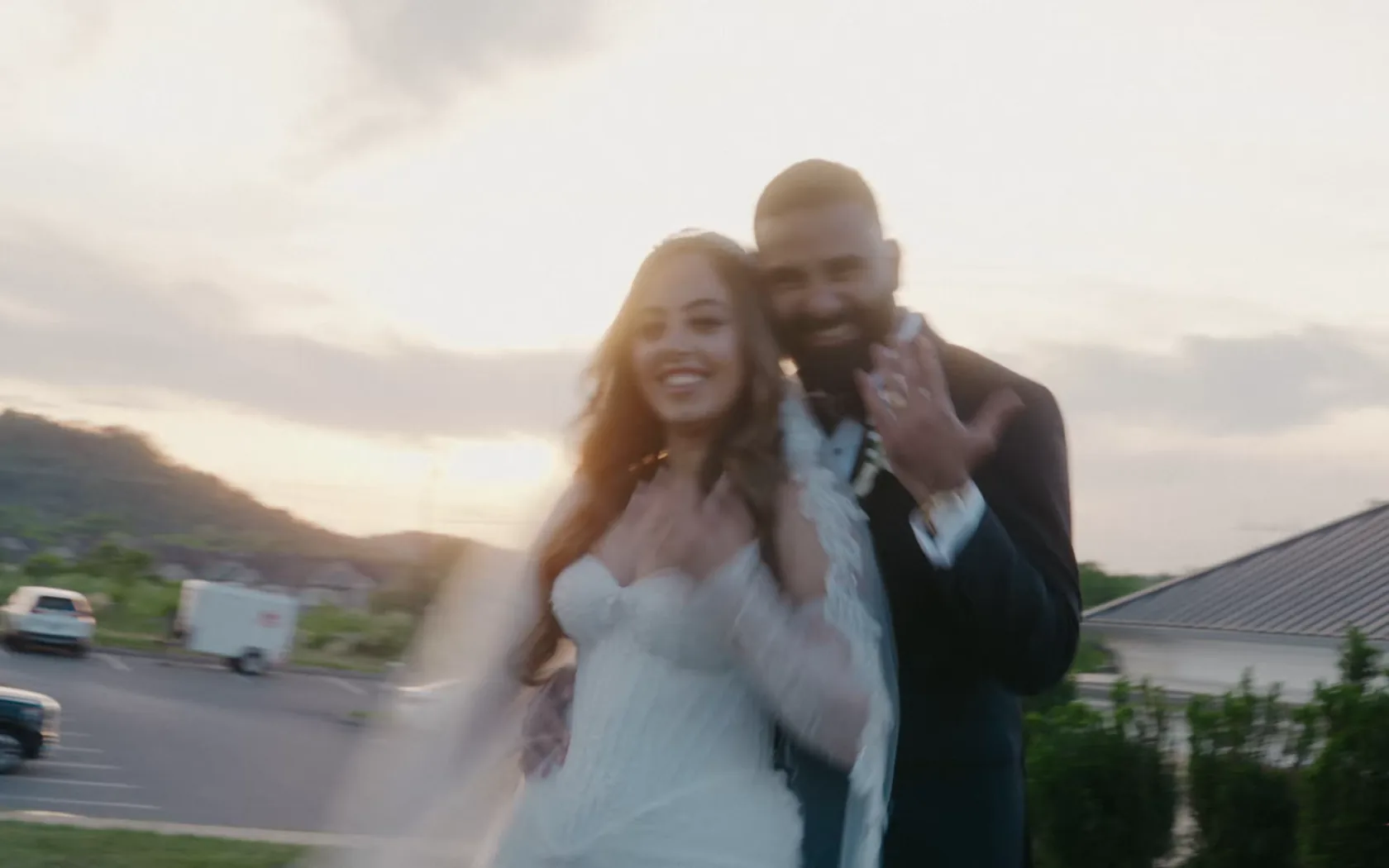Kiro & Sandi at golden hour, her veil sweeping behind them as they smile at each other with the hills beyond