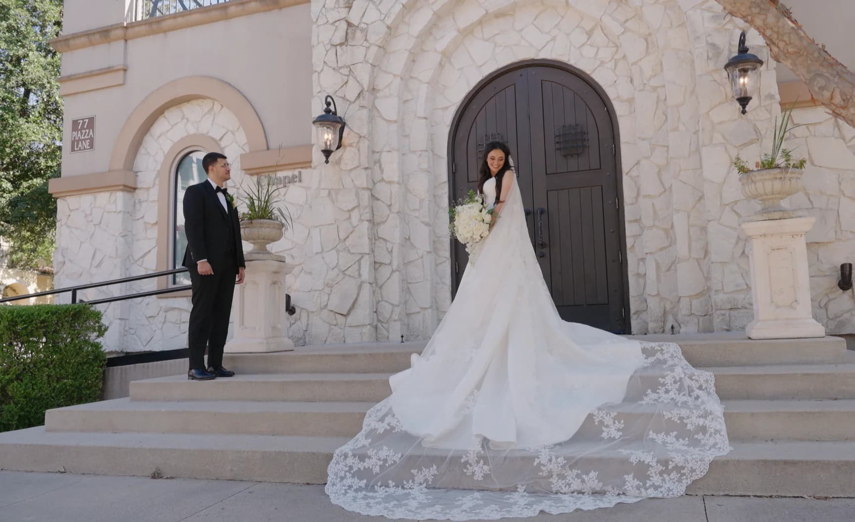 A bride's dress spread across the steps of a small chapel.