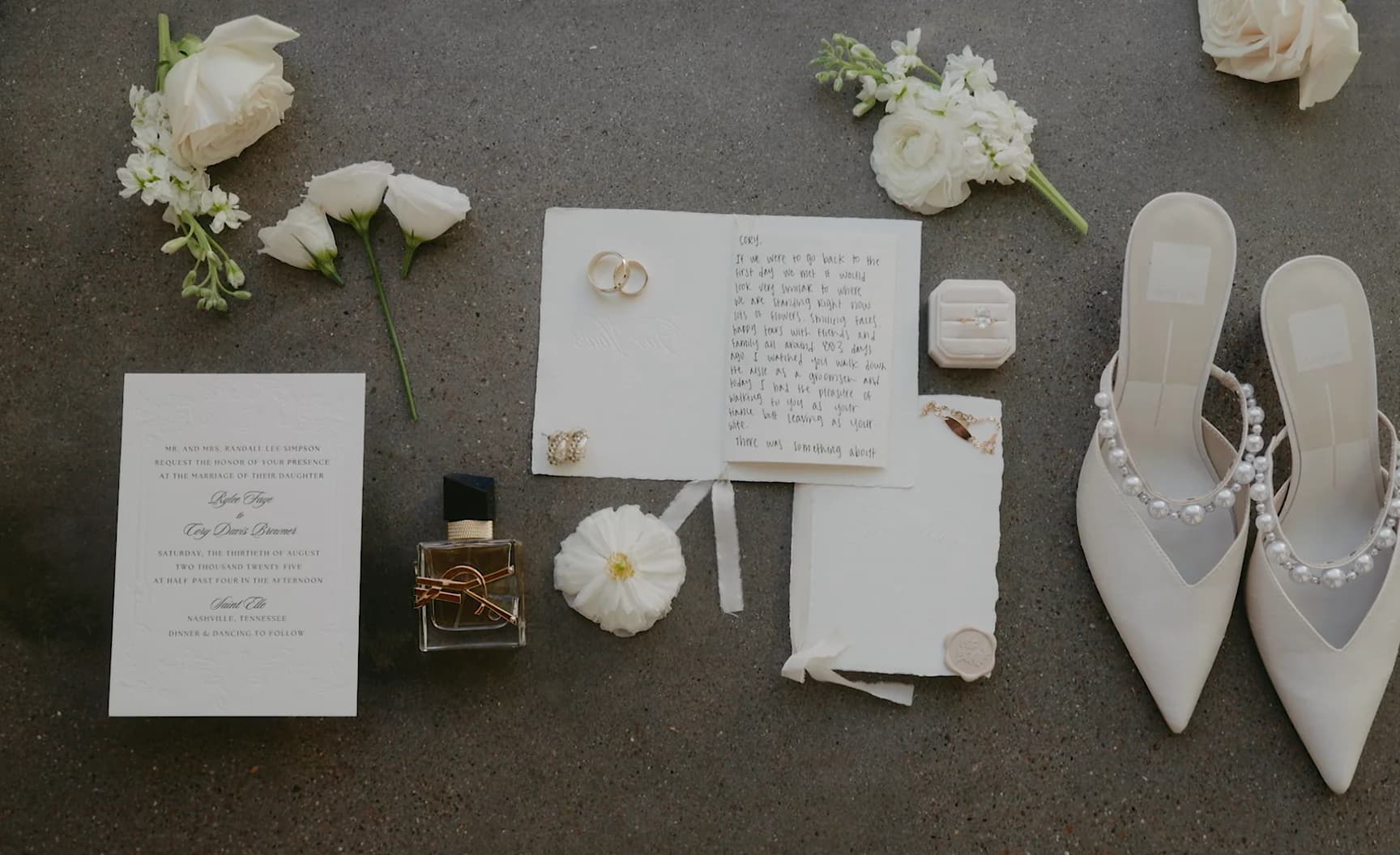 Invitation, rings, shoes and perfume arranged for a detail photo.