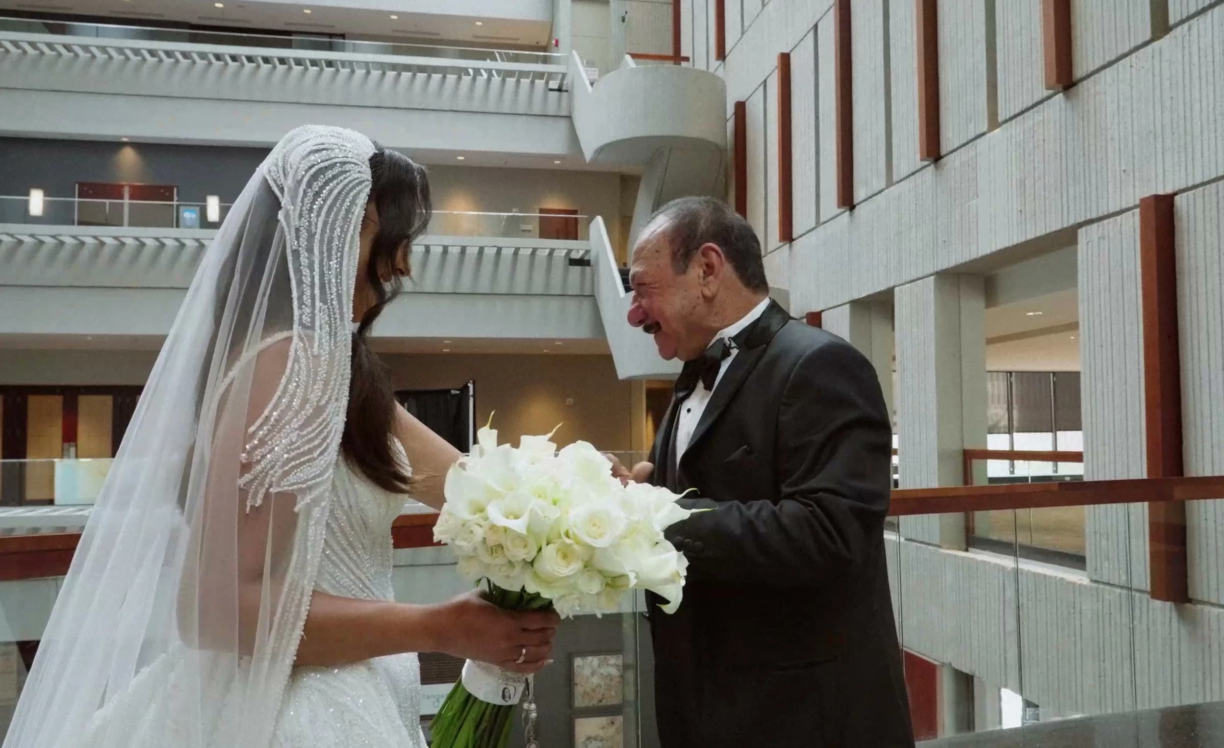 An older man in a tuxedo is overcome as he sees the bride in her veil for the first time