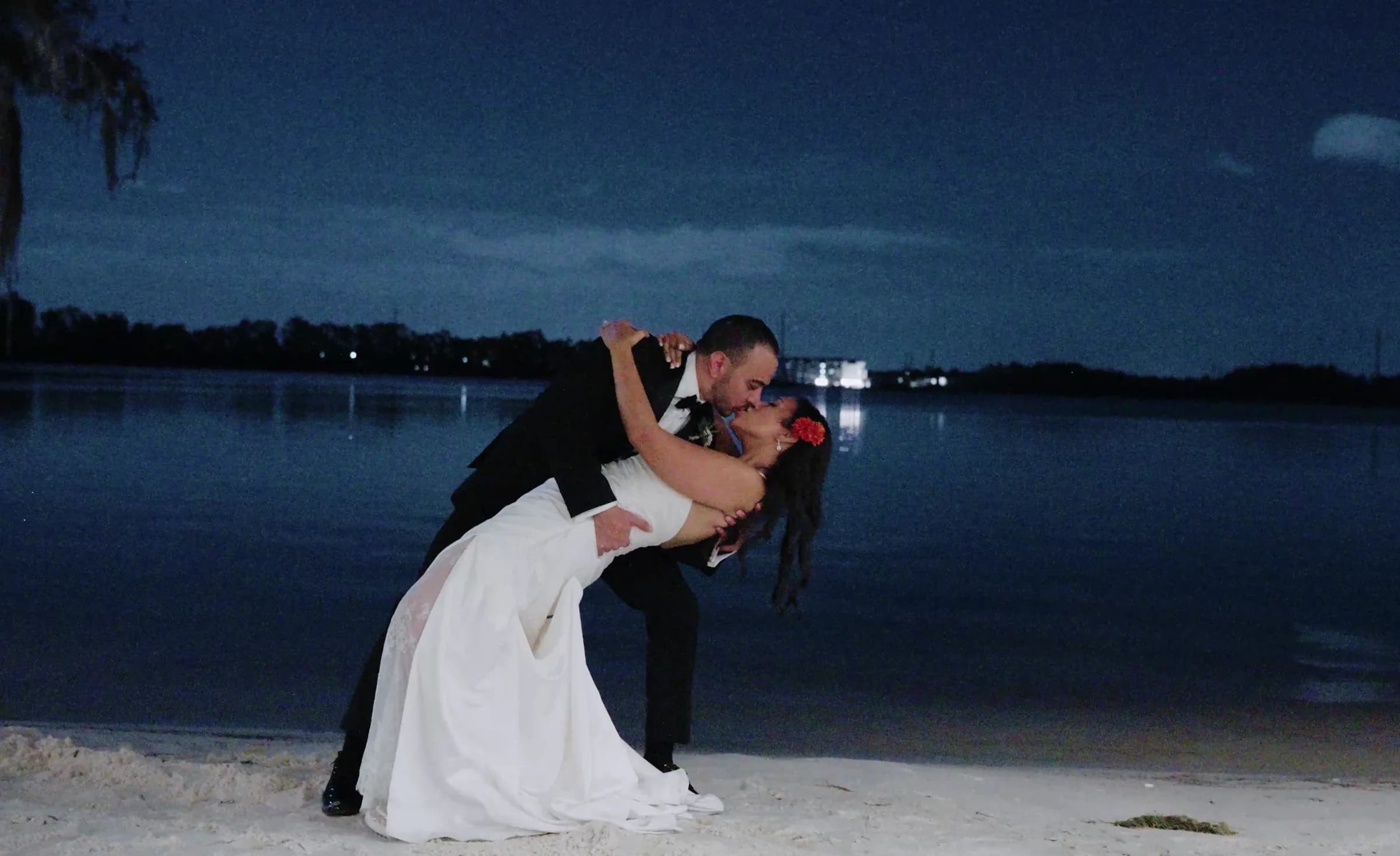 A couple kiss in a dip on a beach at blue hour.