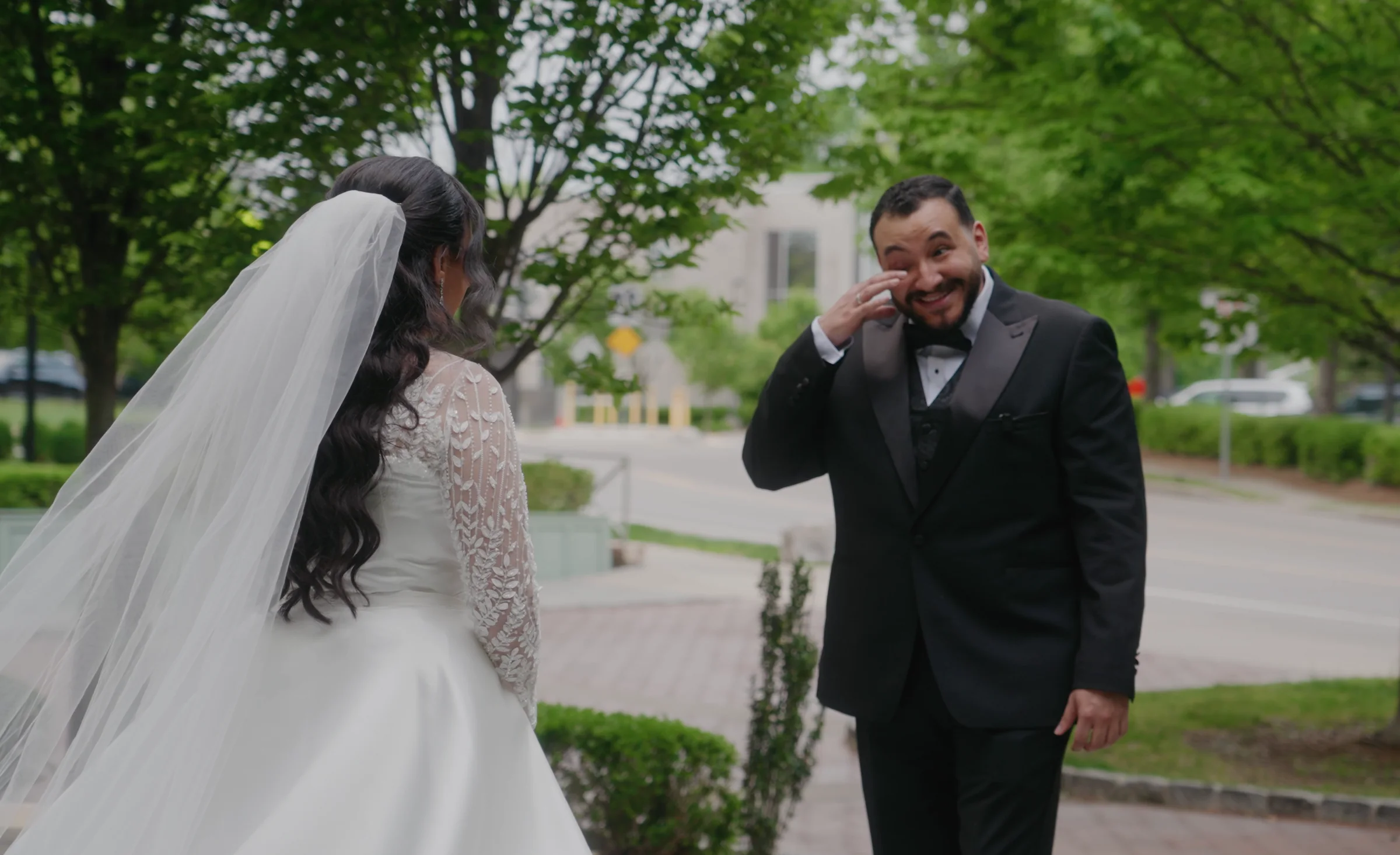 A man wipes his eyes as the bride walks toward him